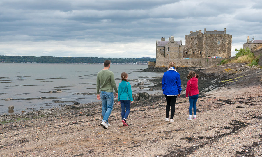 Family walking along beach towards Blackness Castle